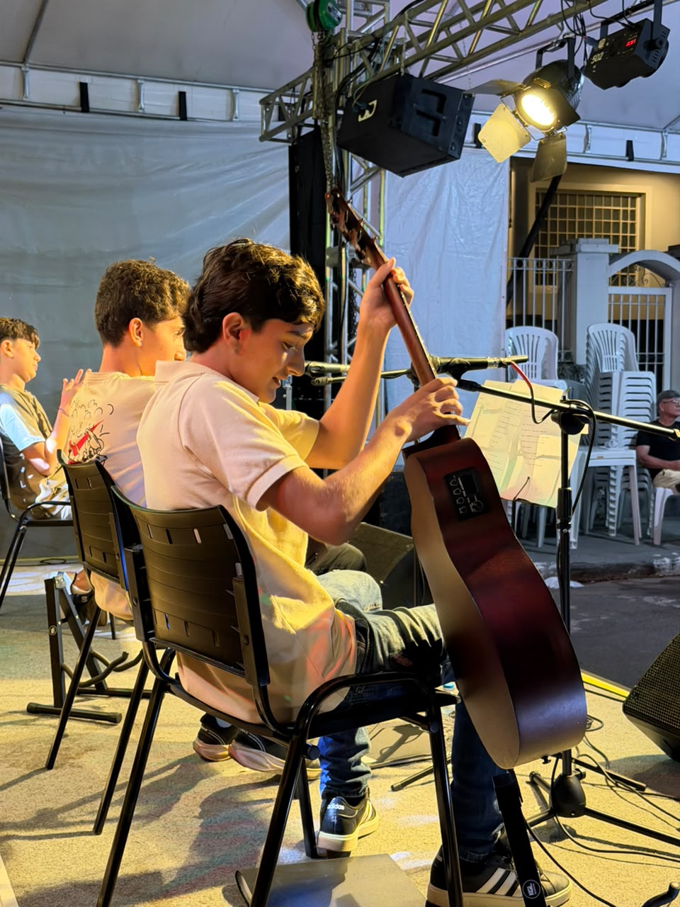 Aluno com violão no palco